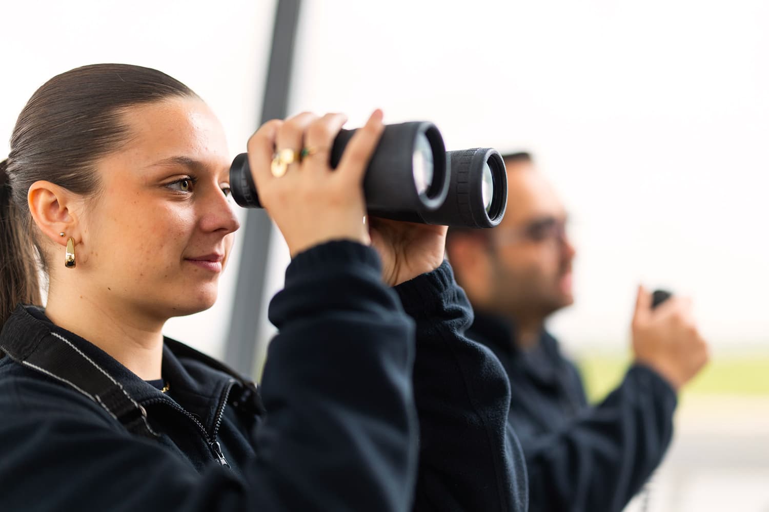 Deux collaborateurs Sabena technics observant les mouvements sur le tarmac, illustrant les opportunités de mobilité, la formation continue et un environnement stimulant