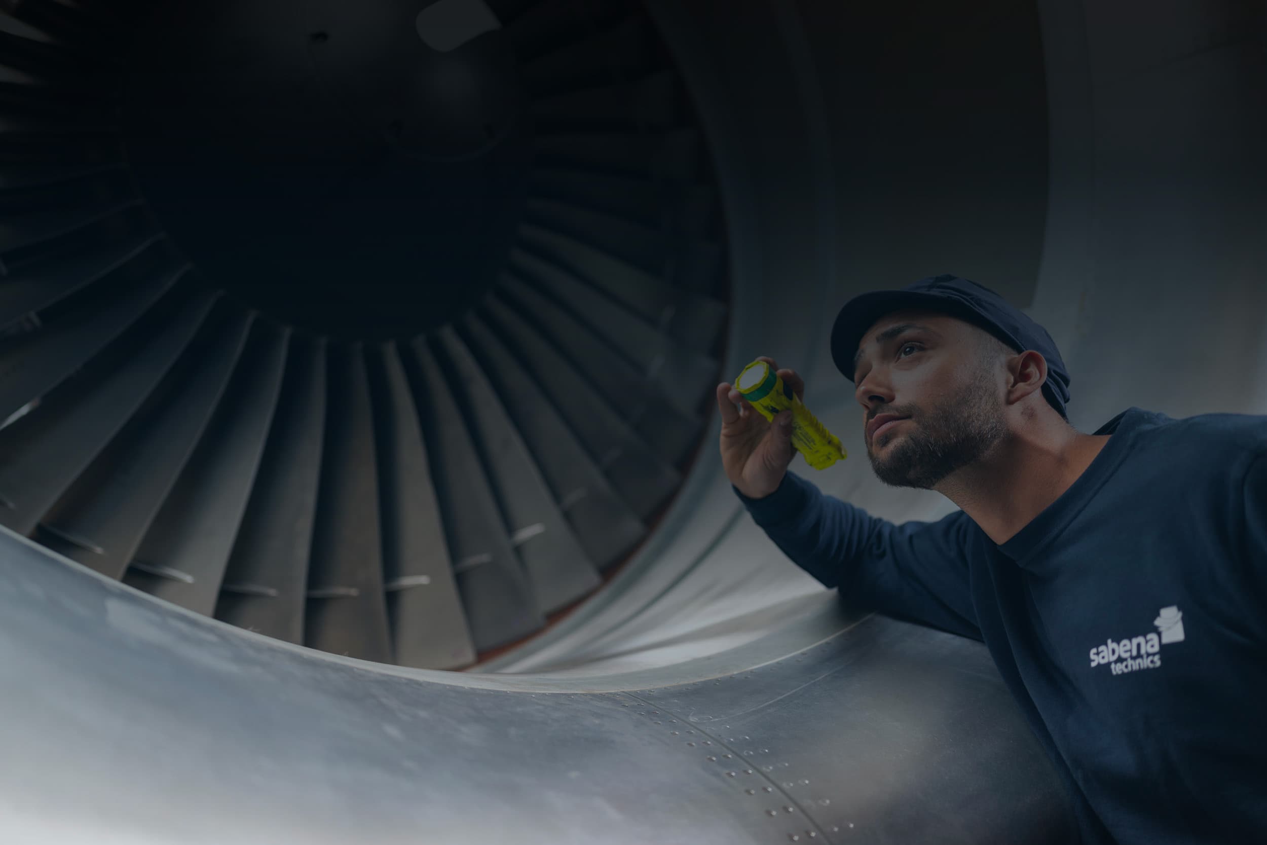Technicien Sabena technics inspectant une turbine de réacteur avec une lampe torche