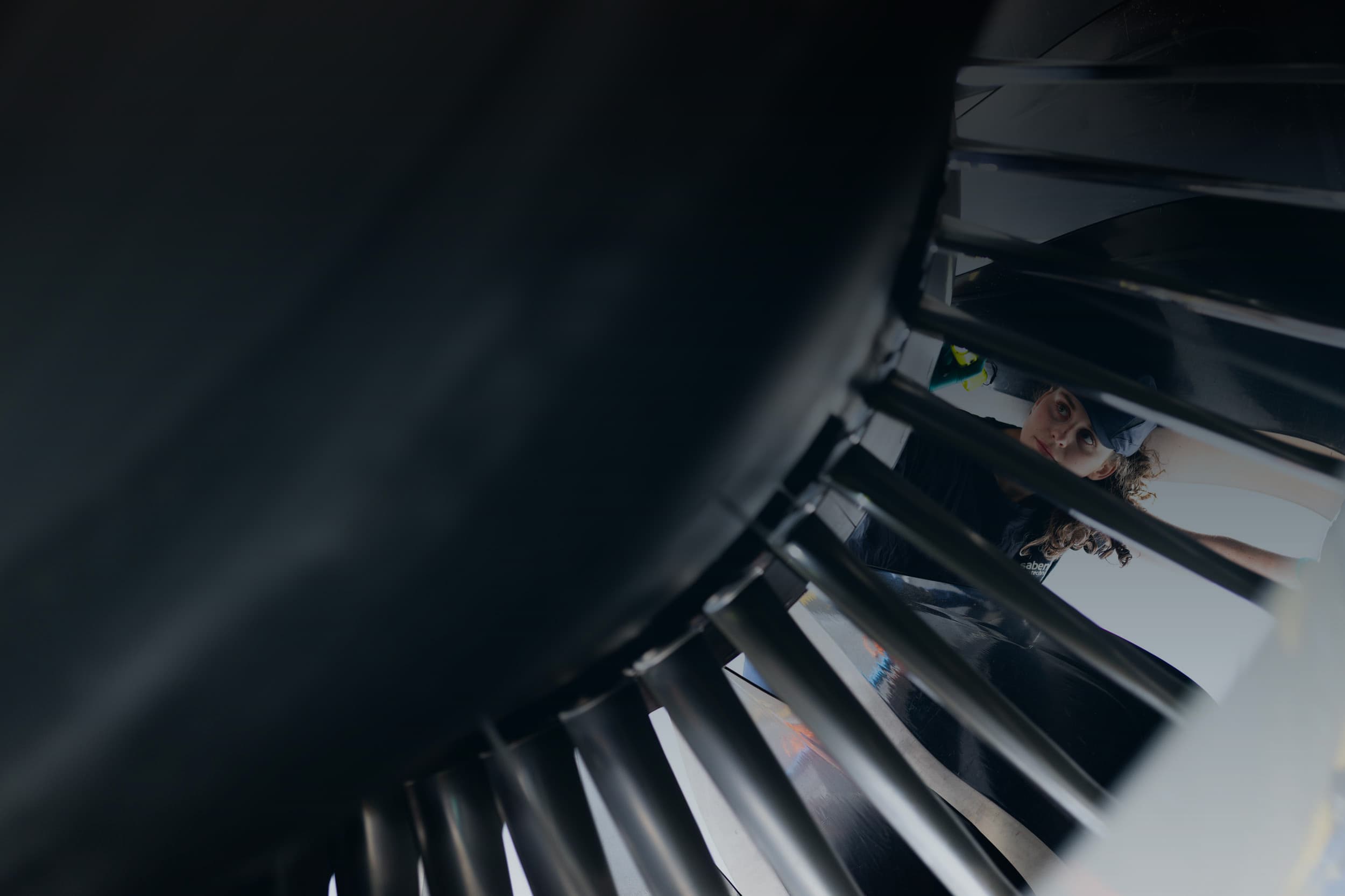 Sabena technics female technician inspecting an aircraft engine, viewed through the fan blades